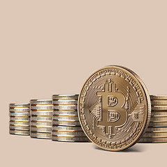 Image showing Cryptocurrency physical bitcoin gold coin and stacks of coins on backgound