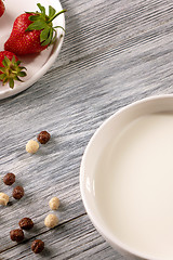 Image showing Ripe strawberries, cereal balls and a plate of milk on a gray wooden table. Top view