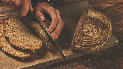 Image showing Baker man slices bread