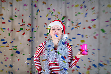 Image showing business woman wearing a red hat and blowing party whistle