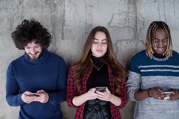 Image showing casual multiethnic business team using mobile phones in front of