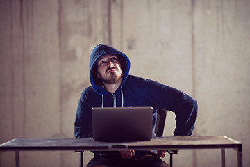 Image showing talented hacker using laptop computer while working in dark offi