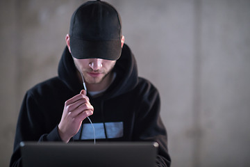 Image showing talented hacker using laptop computer while working in dark offi