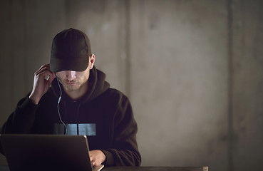 Image showing talented hacker using laptop computer while working in dark offi