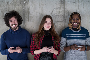 Image showing casual multiethnic business team using mobile phones in front of