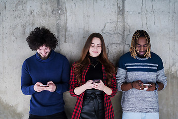 Image showing casual multiethnic business team using mobile phones in front of