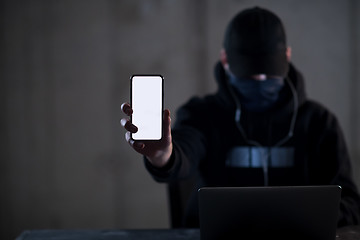 Image showing criminal hacker using laptop computer while working in dark offi