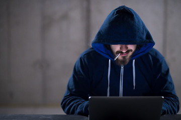 Image showing young hacker using laptop computer while working in dark office