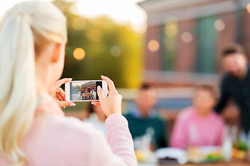 Image showing woman photographing friends by smartphone at party