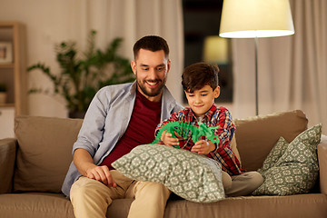 Image showing father and son playing with toy dinosaur at home