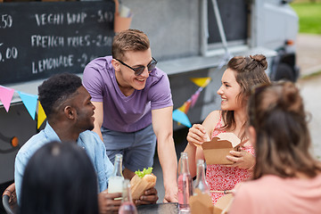 Image showing happy friends with drinks eating at food truck