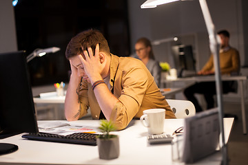 Image showing stressed man at computer monitor at night office