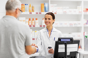 Image showing apothecary selling drug to senior man at pharmacy