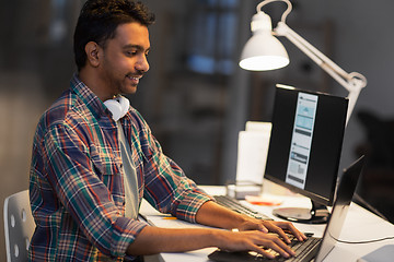 Image showing creative man with laptop working at night office