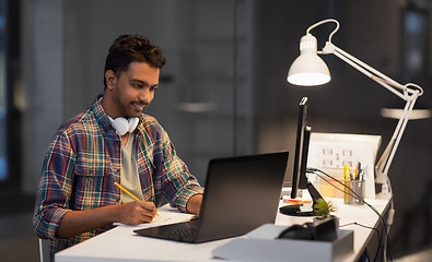 Image showing creative man with laptop working at night office