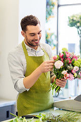 Image showing smiling florist man making bunch at flower shop