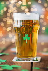 Image showing close up of glass of beer with shamrock on table