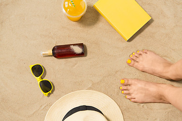 Image showing feet, hat, shades, sunscreen and juice on beach