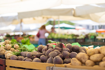 Image showing Farmers\' food market stall with variety of organic vegetable. Vendor serving and chating with customers