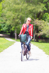 Image showing Happy young woman riding a bicycle in the park.