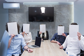 Image showing startup business team holding a white paper over face