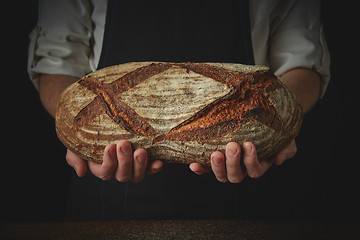 Image showing Men\'s hands hold organic dark bread