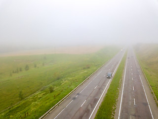 Image showing Aerial view photo from the drone, landscape view of the fields and the road with cars in the fog