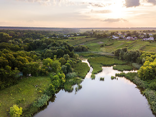 Image showing Beautiful countryside landscape with village, forest, fields, river against summer cloudy sky at sunset.