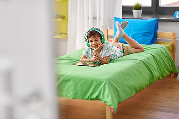 Image showing smiling boy with tablet pc and headphones at home