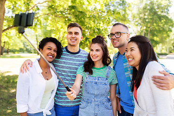 Image showing happy friends taking photo by selfie stick at park