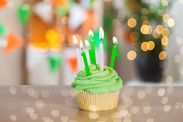 Image showing green cupcake with six burning candles on table