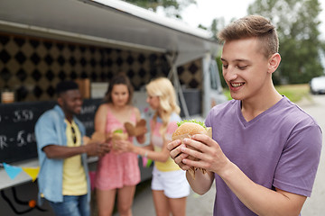 Image showing happy man with hamburger and friends at food truck