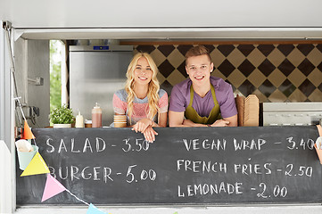 Image showing couple of happy young sellers at food truck