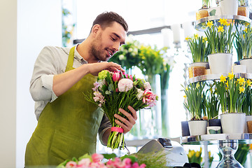 Image showing smiling florist man making bunch at flower shop