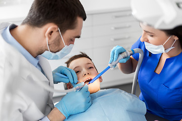 Image showing dentist treating kid teeth at dental clinic