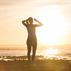 Image showing Woman on sandy beach watching sunset.