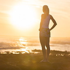 Image showing Woman on sandy beach watching sunset.