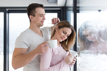 Image showing young couple enjoying morning coffee by the window