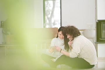 Image showing multiethnic couple using tablet computer in front of fireplace