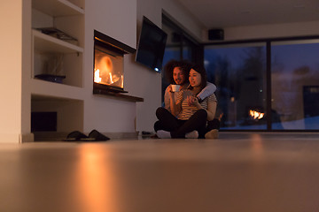 Image showing happy multiethnic couple sitting in front of fireplace