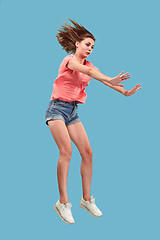 Image showing Freedom in moving. Pretty young woman jumping against blue background