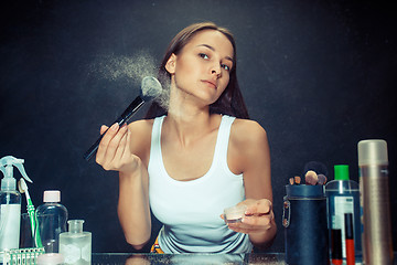 Image showing Beauty woman applying makeup. Beautiful girl looking in the mirror and applying cosmetic with a big brush.