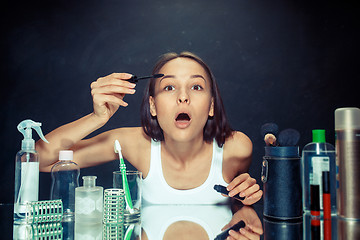 Image showing Beauty woman applying makeup. Beautiful girl looking in the mirror and applying cosmetic with a big brush.