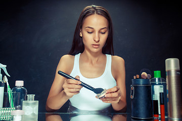 Image showing Beauty woman applying makeup. Beautiful girl looking in the mirror and applying cosmetic with a big brush.