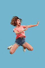 Image showing Freedom in moving. Pretty young woman jumping against blue background