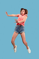 Image showing Freedom in moving. Pretty young woman jumping against blue background