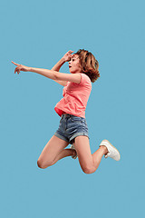 Image showing Freedom in moving. Pretty young woman jumping against blue background