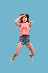 Image showing Freedom in moving. Pretty young woman jumping against blue background