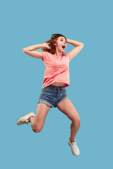 Image showing Freedom in moving. Pretty young woman jumping against blue background