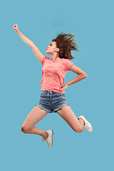 Image showing Freedom in moving. Pretty young woman jumping against blue background